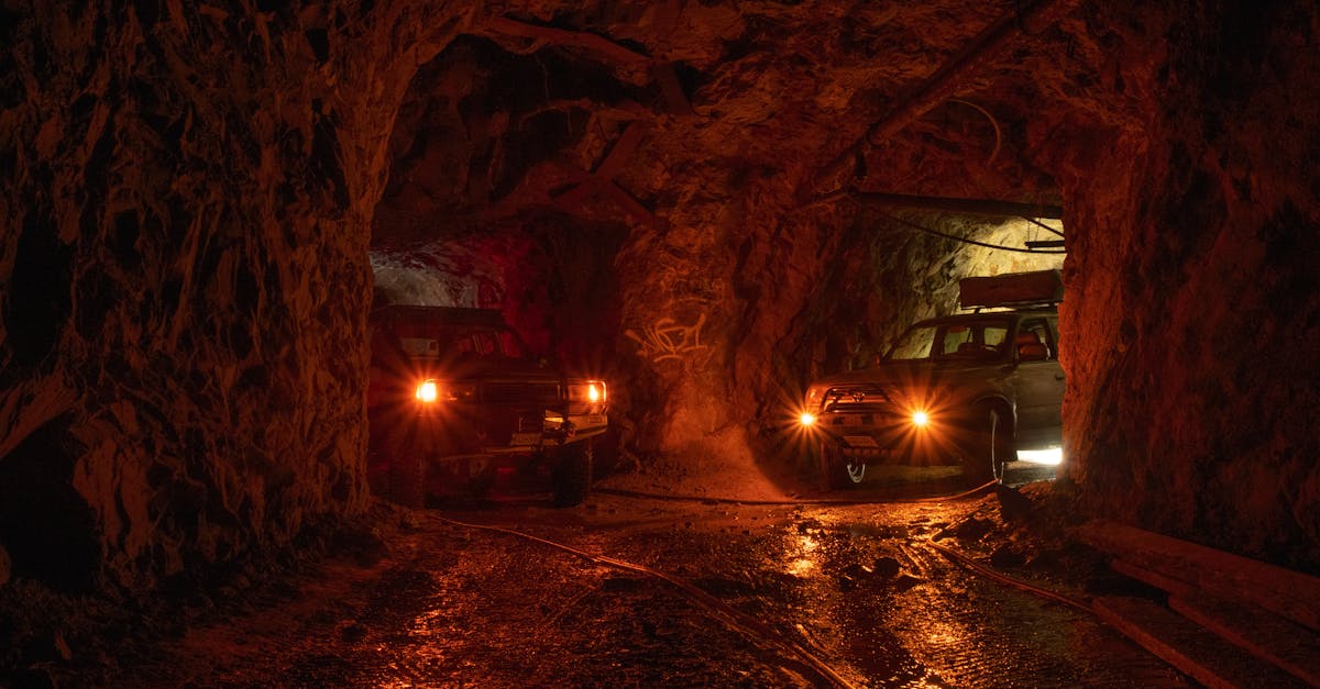 Two SUVs with headlights on parked in a dimly lit underground cave in BC, Canada.