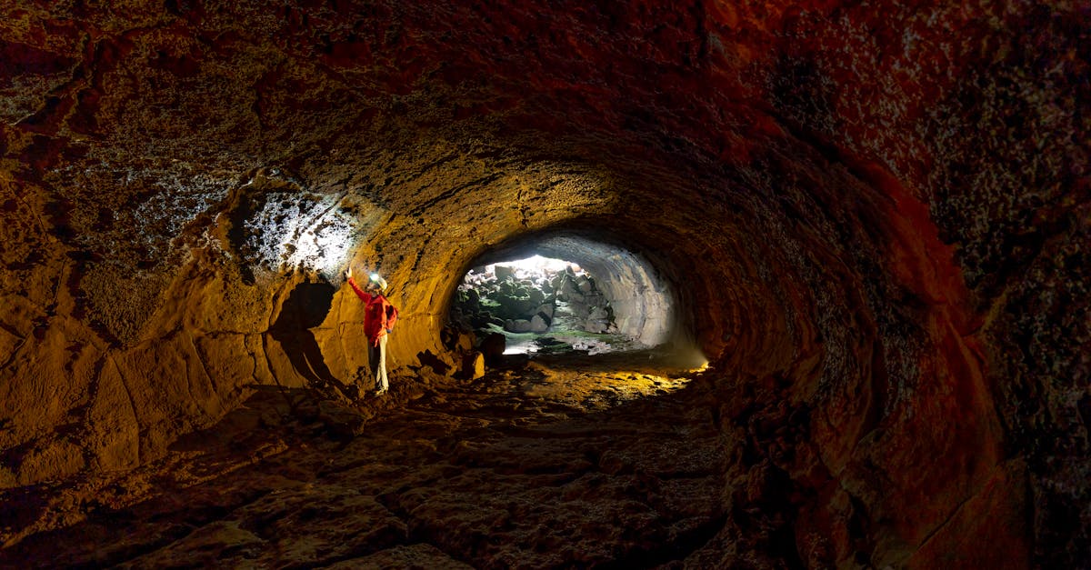 A person exploring a rugged cave with a flashlight, revealing textured walls.
