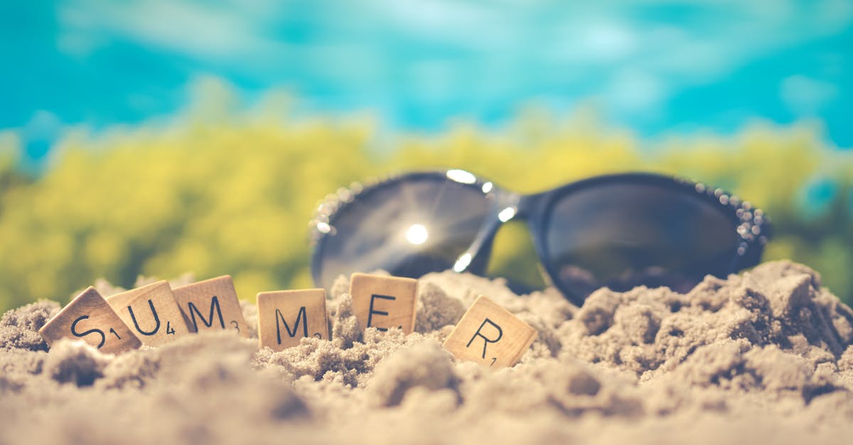 Sandy beach scene with sunglasses and 'summer' spelled in letter tiles, capturing vacation vibes.