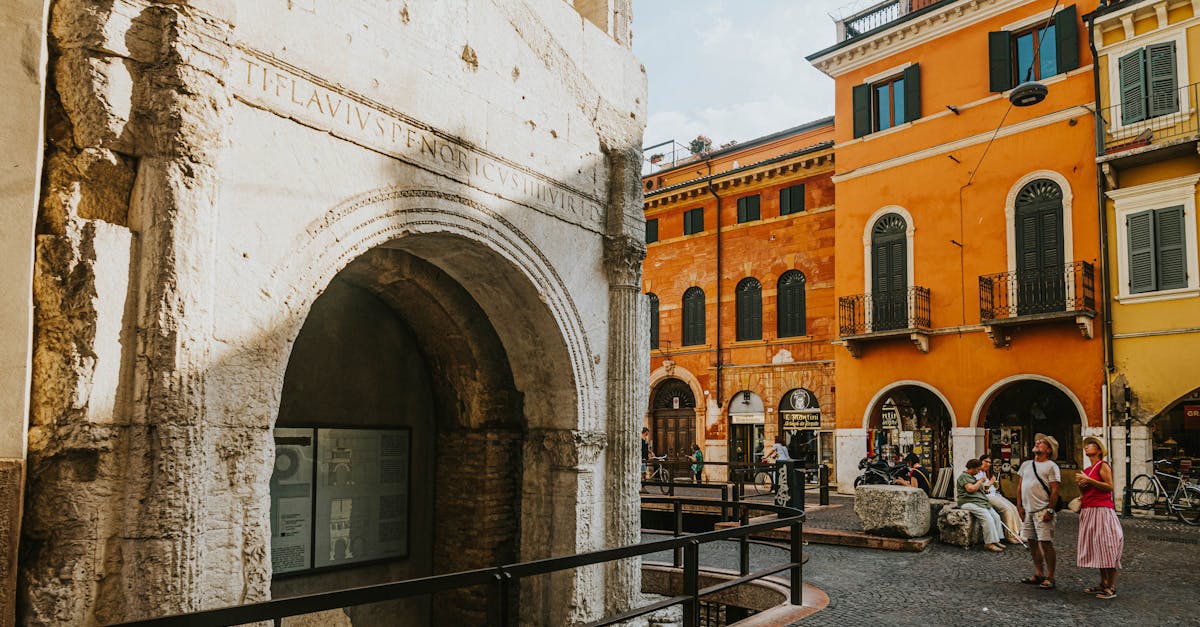 Explore a vibrant street in Verona, Italy, featuring a Roman arch and colorful historic architecture.