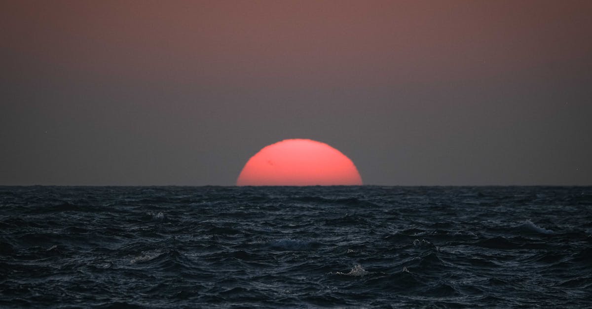 Capture of a vibrant red sunset over a dark ocean, highlighting the natural beauty of golden hour.