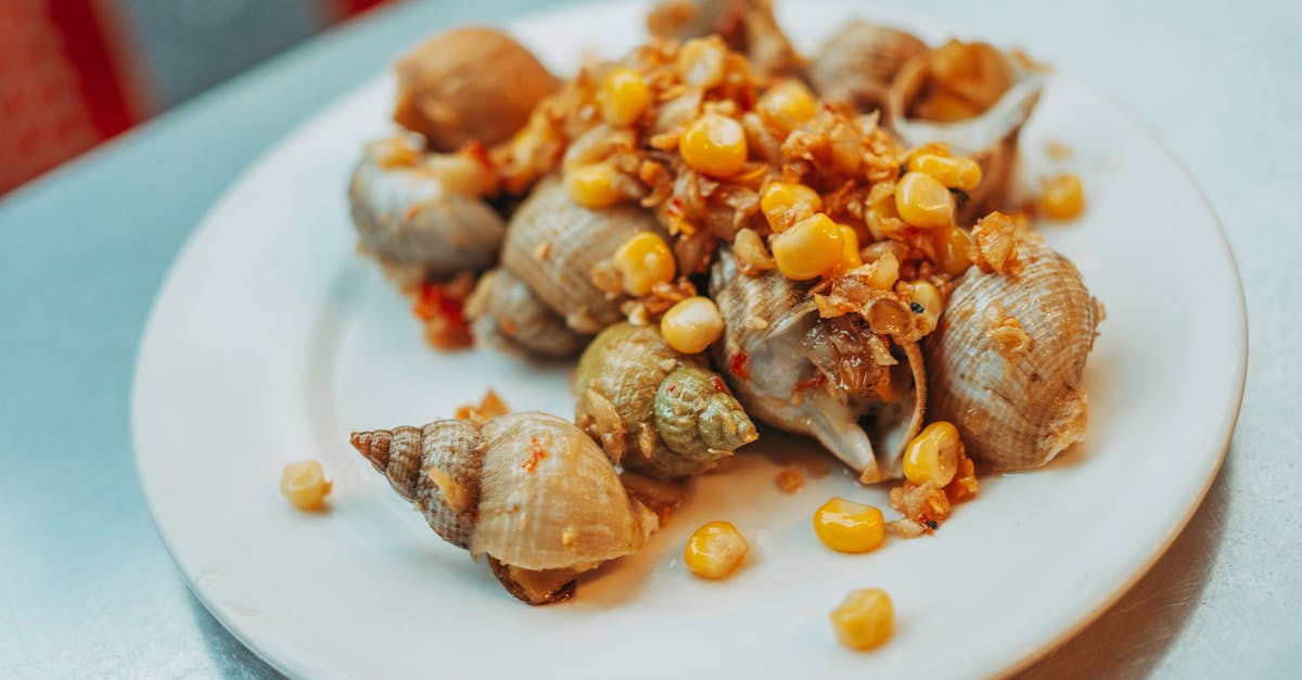 Plate of snails and corn garnished with spices, offering a gourmet seafood experience.
