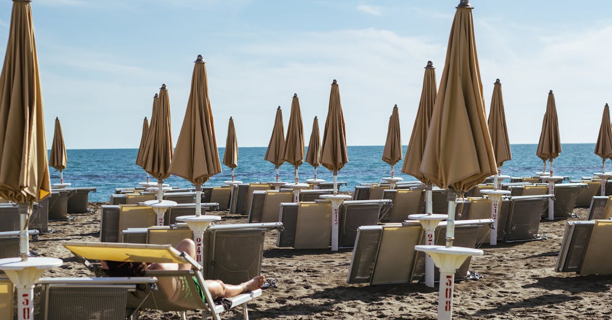 Relax under the sun on a pristine beach in Lazio, Italy, with lined umbrellas and chairs on sandy shores.