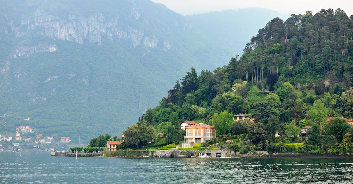 Peaceful morning view of villas by Lake Como with lush greenery and majestic mountains.