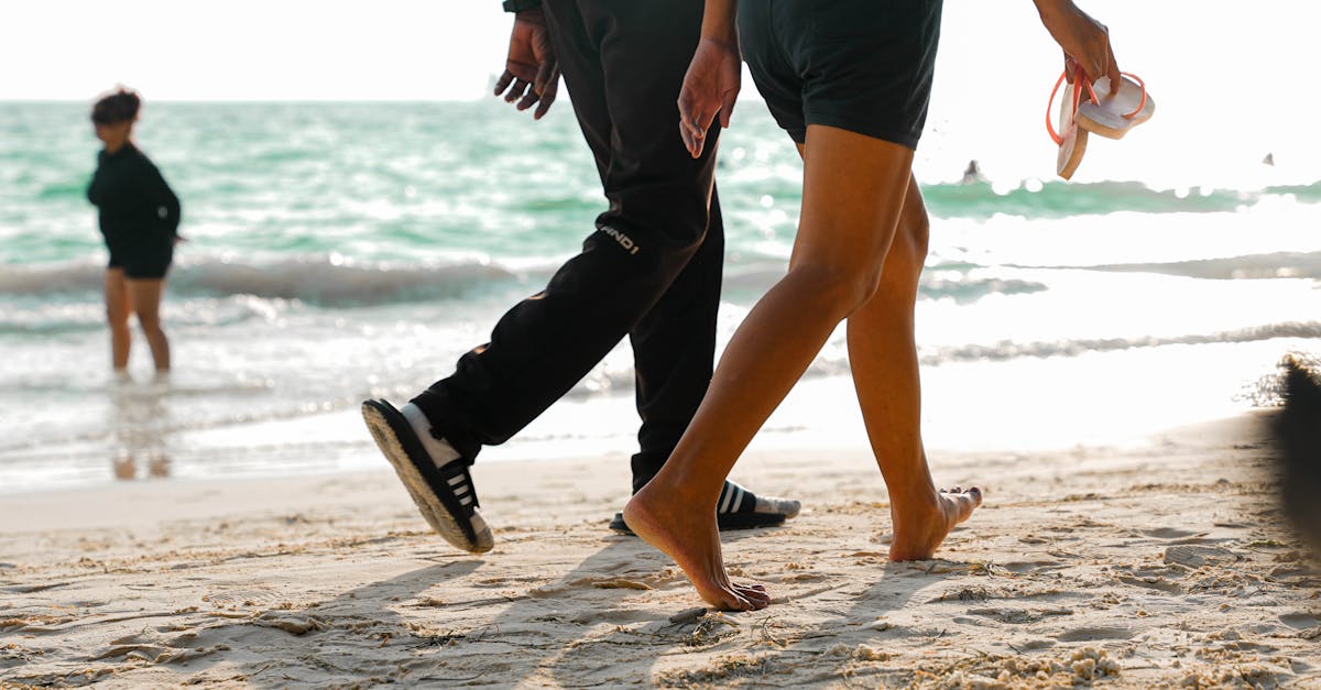 A couple walks barefoot on a sunny beach, enjoying a relaxing seaside day.