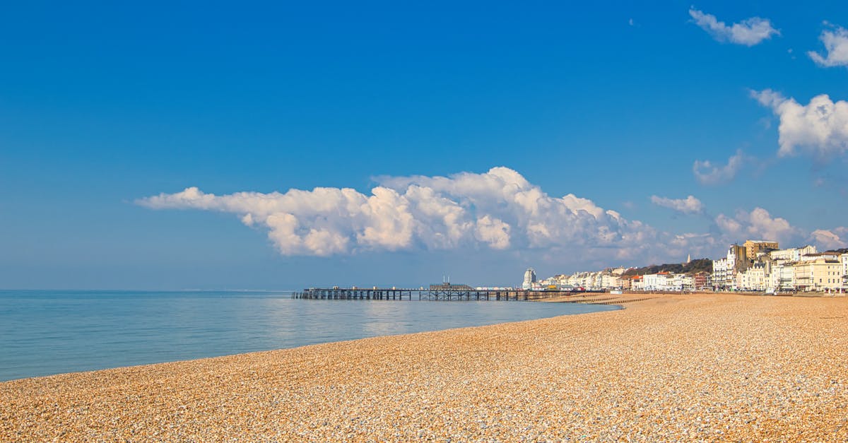 A serene pebble beach with a clear blue sky and a quaint coastal town in the background.