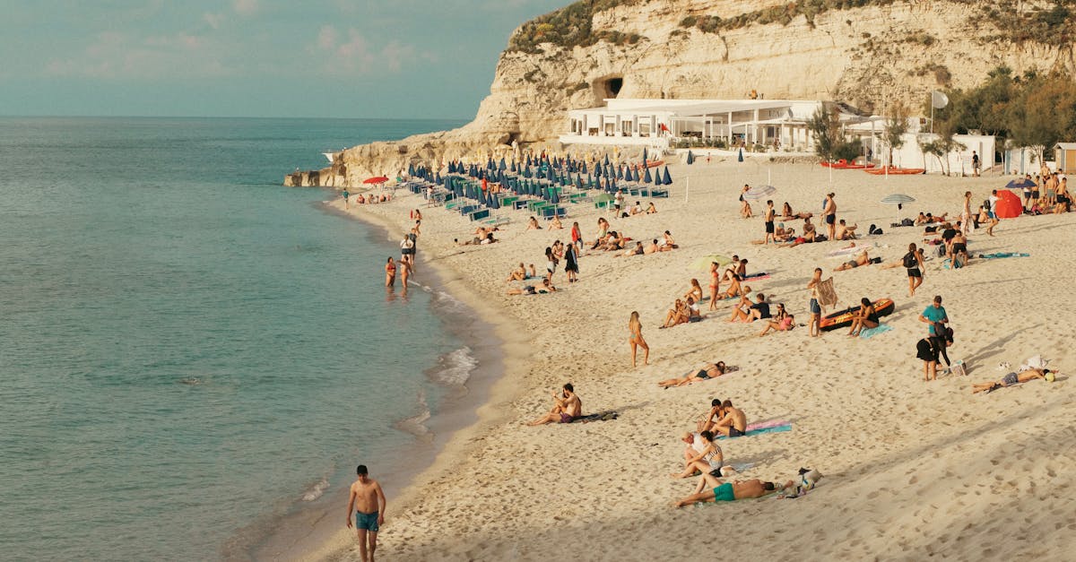 Sunny day at Tropea Beach, Calabria, featuring people enjoying sand and sea.