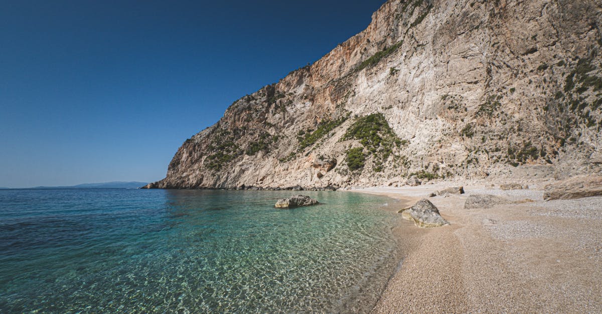 Cliffside beach with clear turquoise waters and sunny skies, perfect for summer travel.