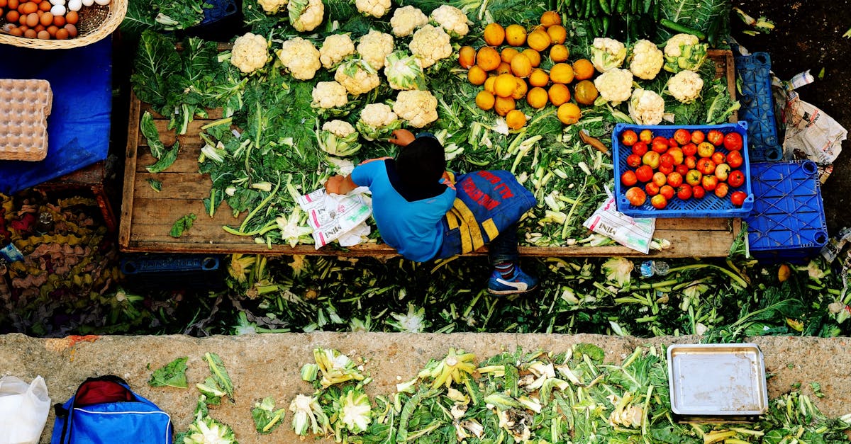 Young vendor at a vibrant market stall in İzmir, Türkiye, displaying fresh produce from above.