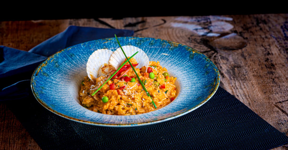Delicious seafood risotto with scallops, peas, and red bell peppers in a vibrant blue bowl.
