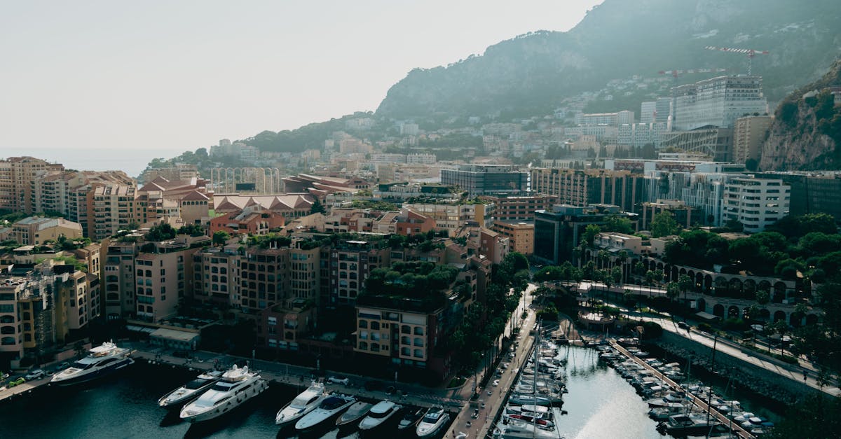 Aerial view of Monaco's Monte Carlo with luxury yachts and mountainous backdrop.