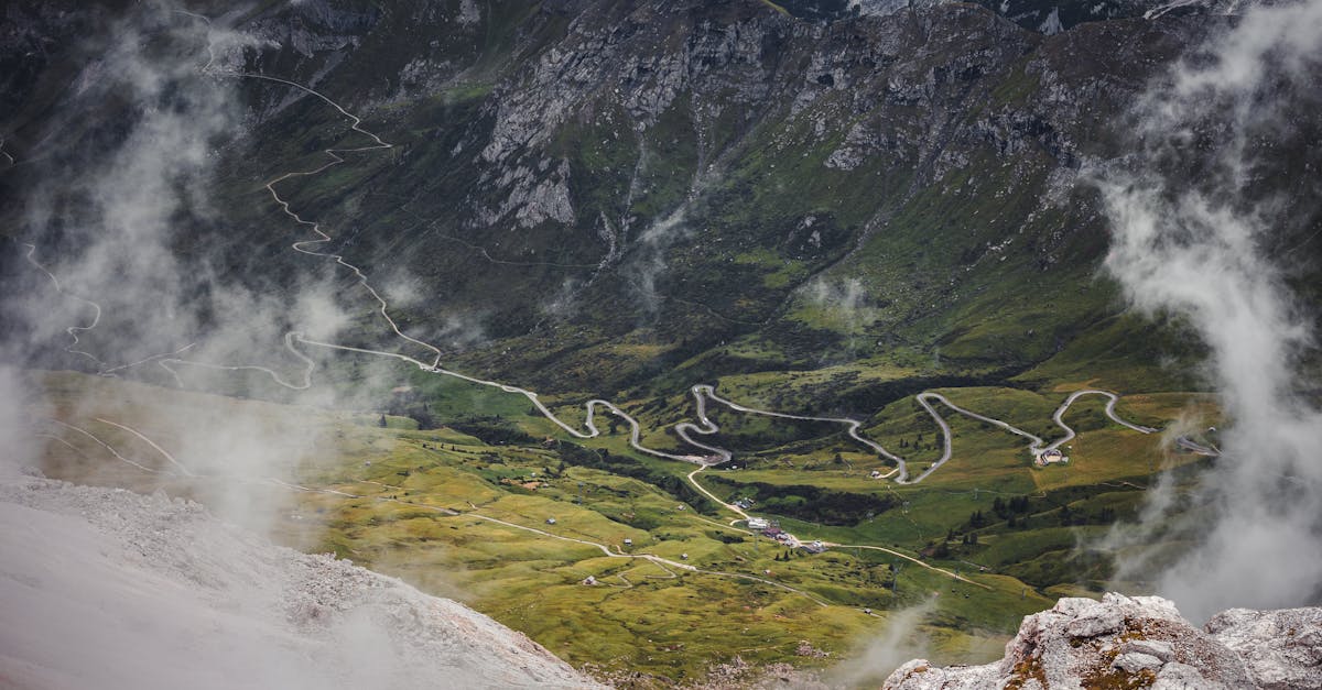 A breathtaking aerial shot of a mountainous landscape with winding roads and lush greenery surrounded by mist.