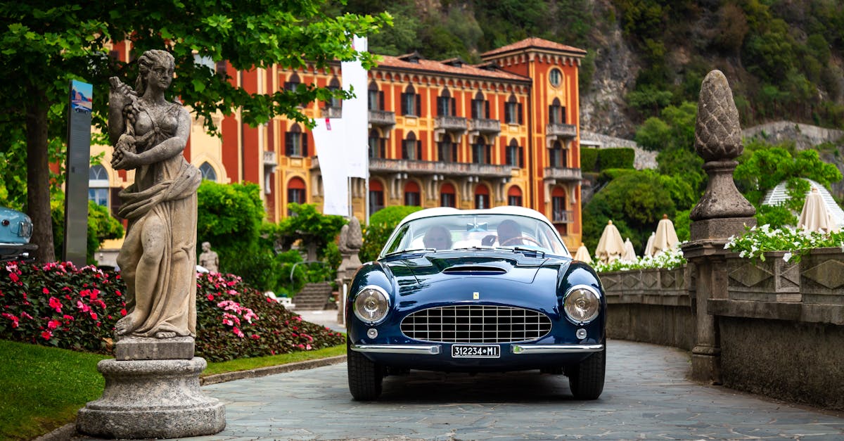 Classic vintage car parked by a sculpture in an Italian villa setting.