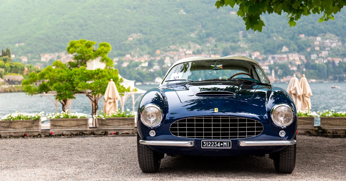 Elegant vintage blue car parked by a picturesque lake, showcasing luxury and classic design.