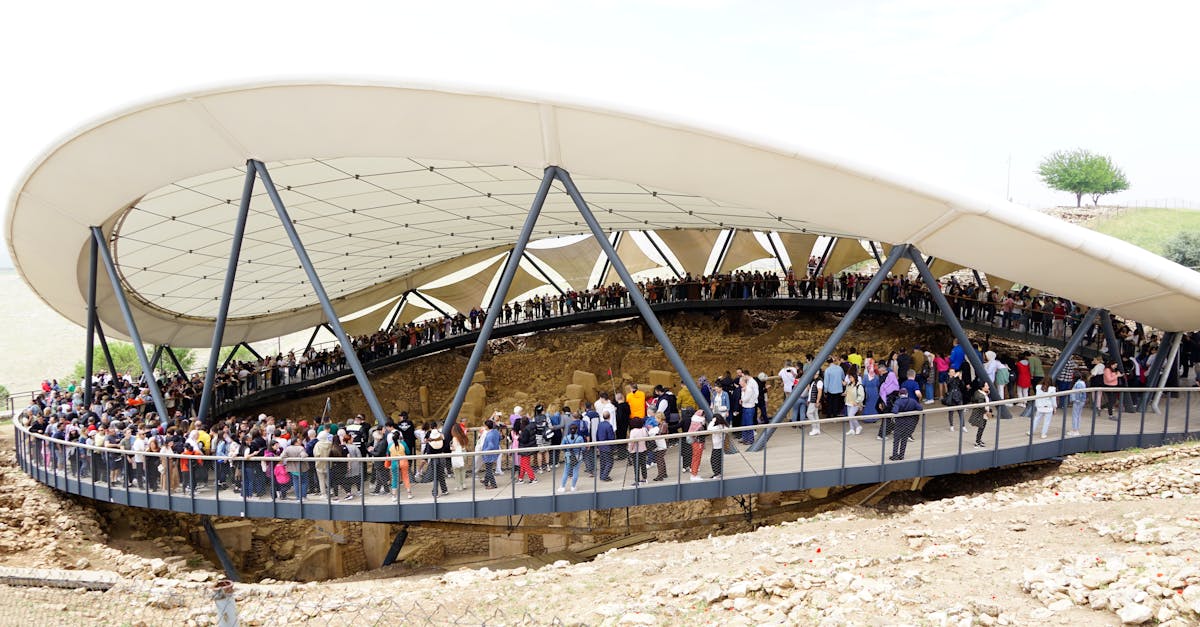 Visitors explore the historical Göbekli Tepe site in Şanlıurfa, Türkiye under a modern canopy.