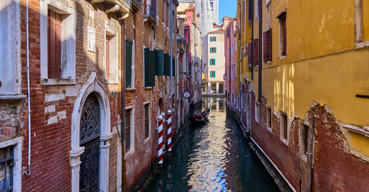 Charming Venetian canal with colorful buildings and a gondola on a sunny day.