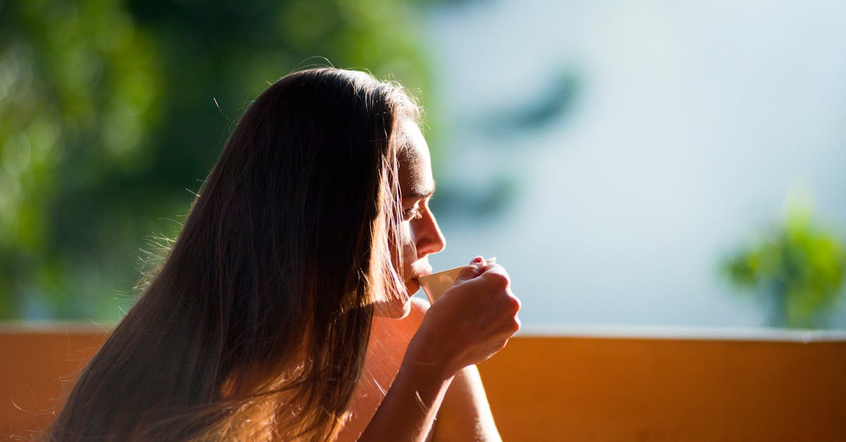 A woman peacefully sipping tea outdoors in the morning sunlight.