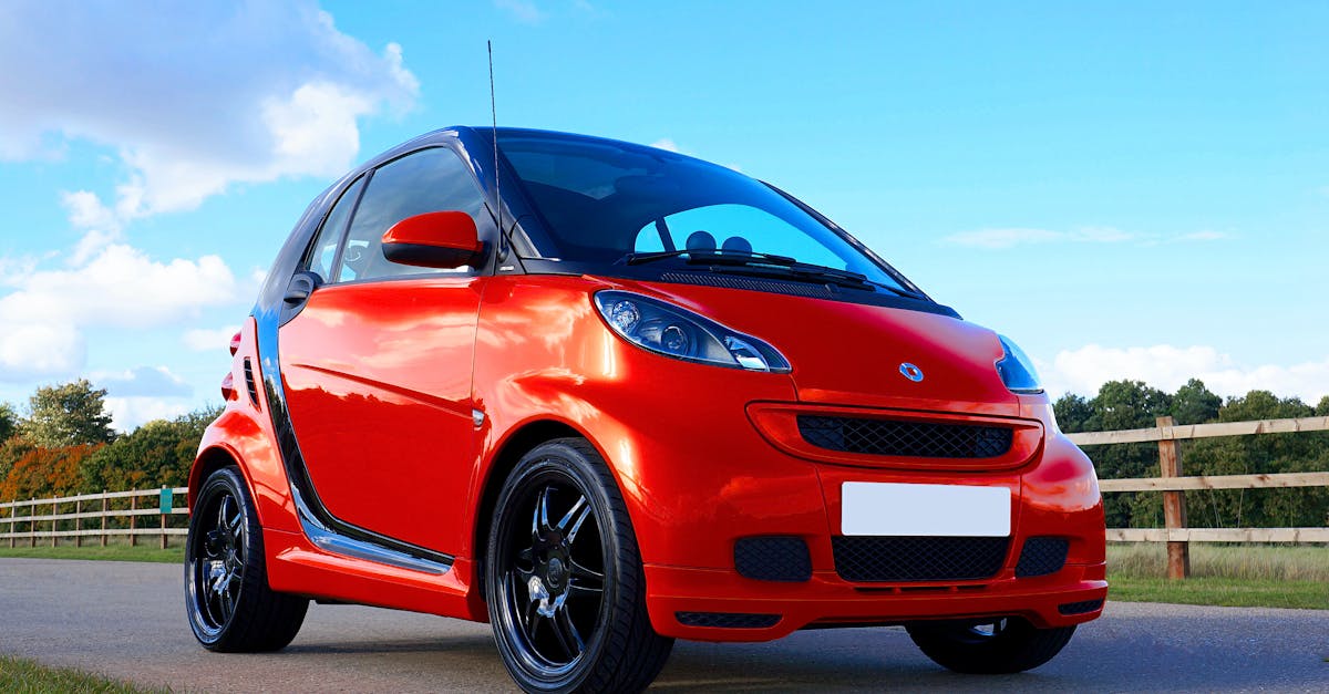 Red compact car parked outdoors on a bright sunny day showcasing stylish design and alloy wheels.