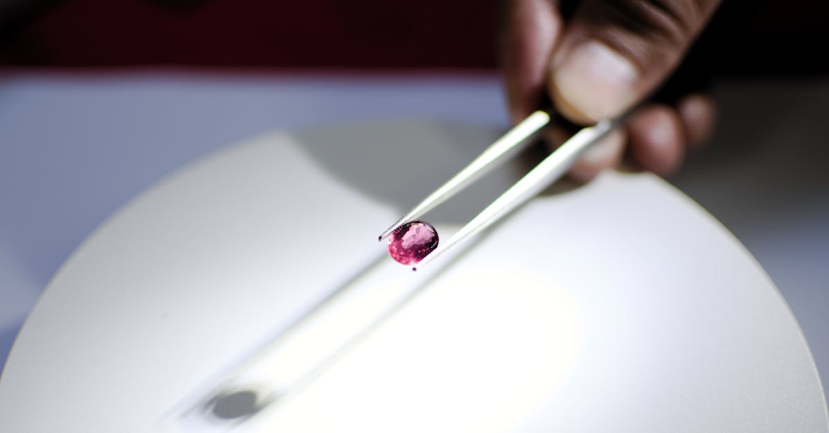 Detailed image of a hand holding a red gemstone using tweezers, perfect for jewelry and gemology themes.