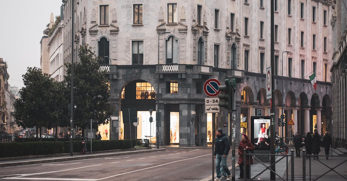 Street view showcasing historic architecture in Milan, Italy with pedestrians and traffic lights.