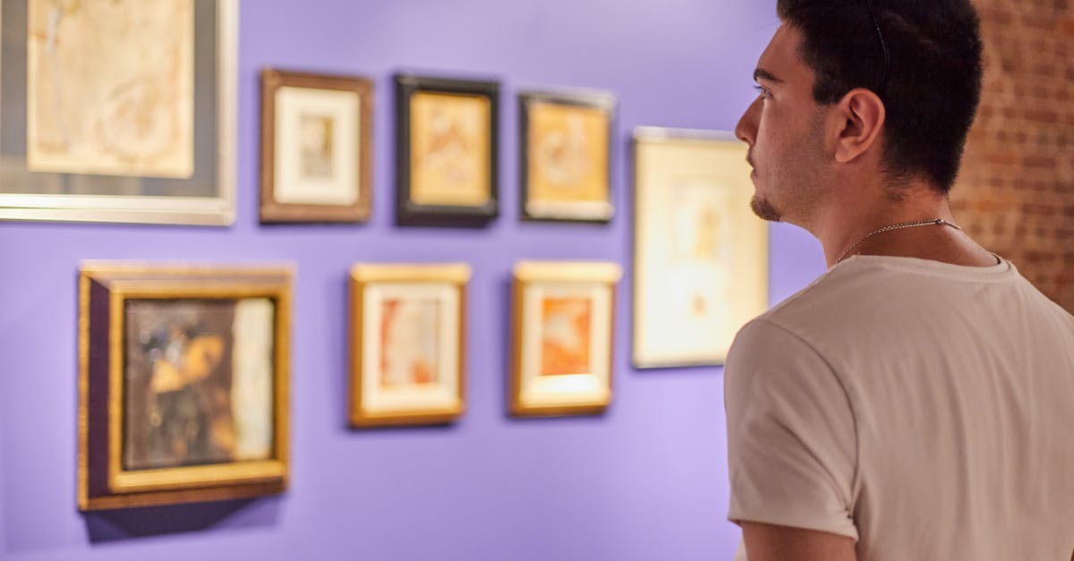 A young man looks at framed art on a vibrant blue wall in an İstanbul gallery.