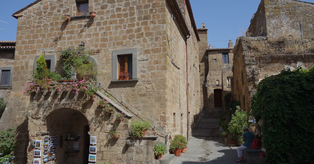 Historic stone building with rustic charm, surrounded by colorful flowers in a quaint Italian alley.