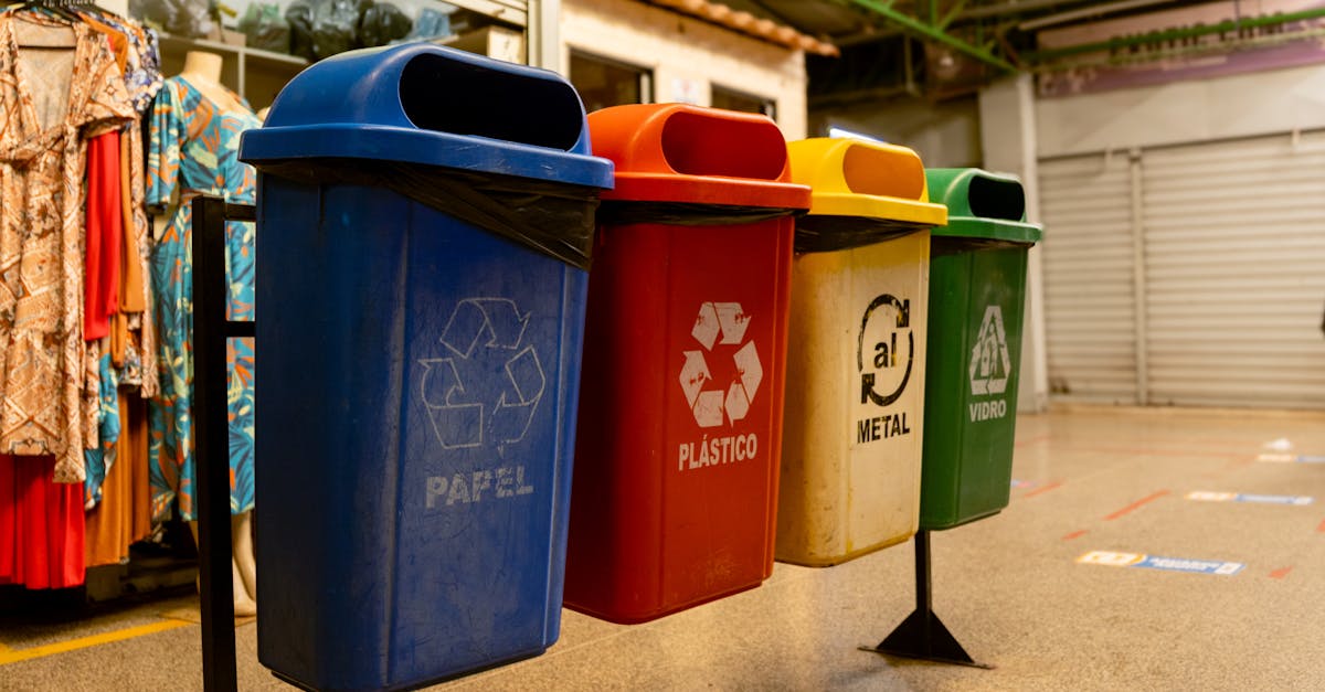 Four recycling bins for paper, plastic, metal, and glass indoors.