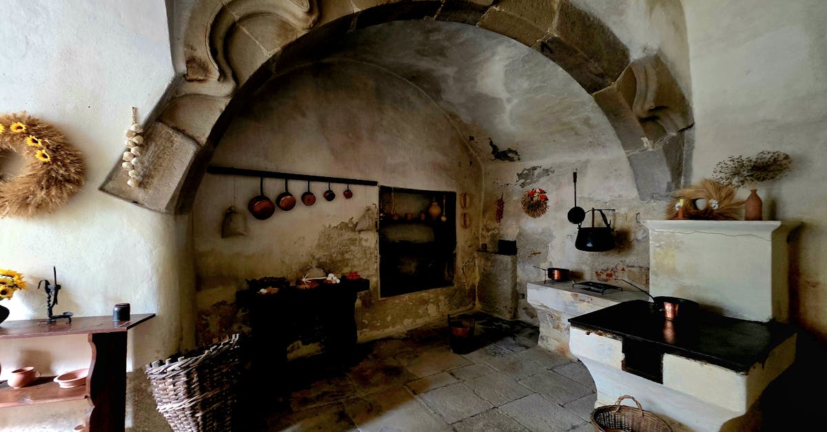 Charming rustic stone kitchen with vintage decor, warm tones, and an antique hearth.