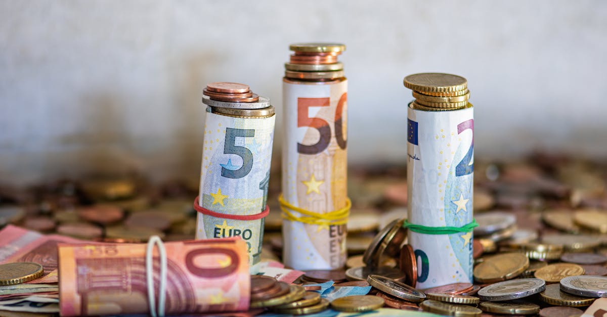 Close-up of rolled Euro banknotes and coins on a table, symbolizing finance and savings.