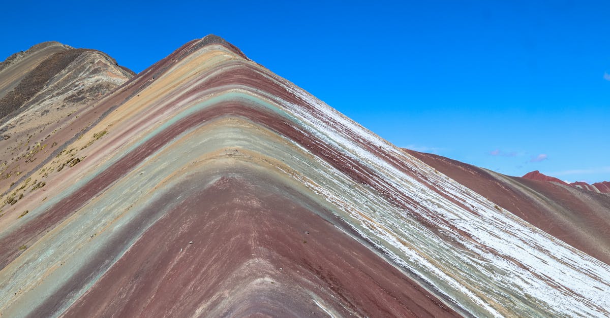 Vibrant Rainbow Mountain in Peru showcasing colorful geological layers under a clear blue sky.