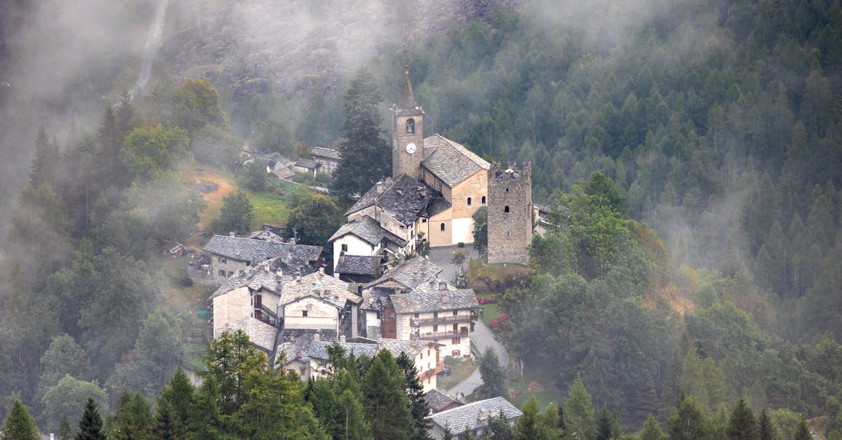 Aerial view of a charming Italian village surrounded by fog and lush greenery.