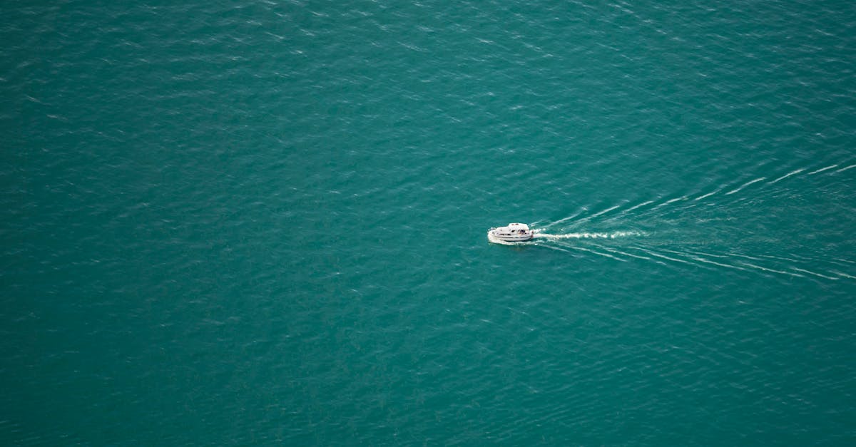 A lone boat sails through expansive turquoise waters, leaving a serene wake behind.