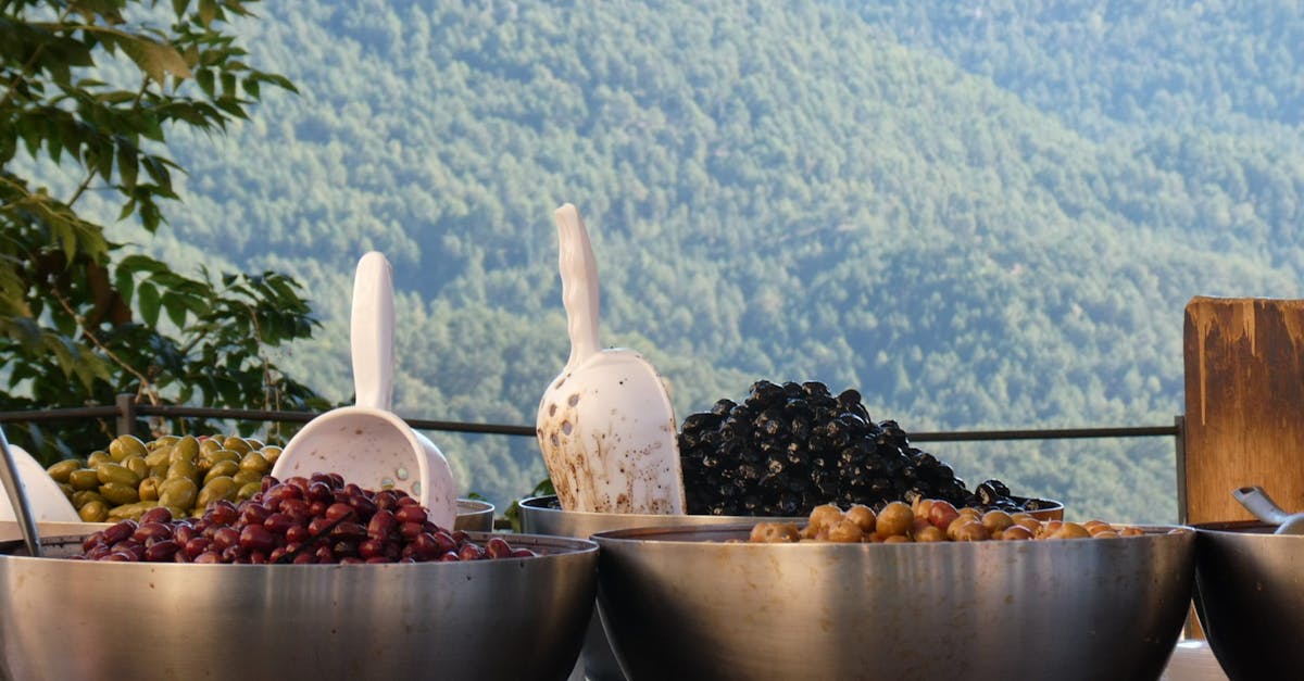 Bowls of assorted olives in a scenic outdoor setting with mountain views.
