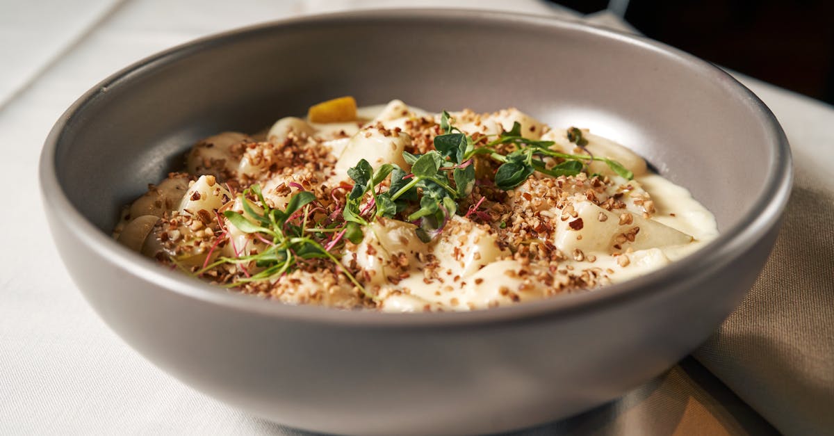A bowl of gnocchi pasta topped with cream sauce and fresh herbs.