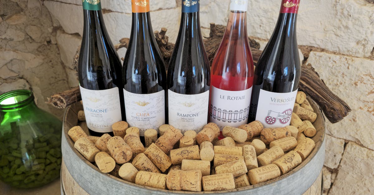 A rustic display of diverse wine bottles and corks on a barrel with a stone wall background.