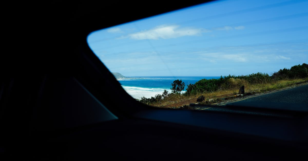 Experience a breathtaking coastal view captured through a car window on a bright, sunny day.