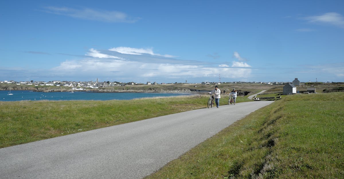 Scenic view of cyclists on a coastal road in Bretagne, France, under a clear blue sky.