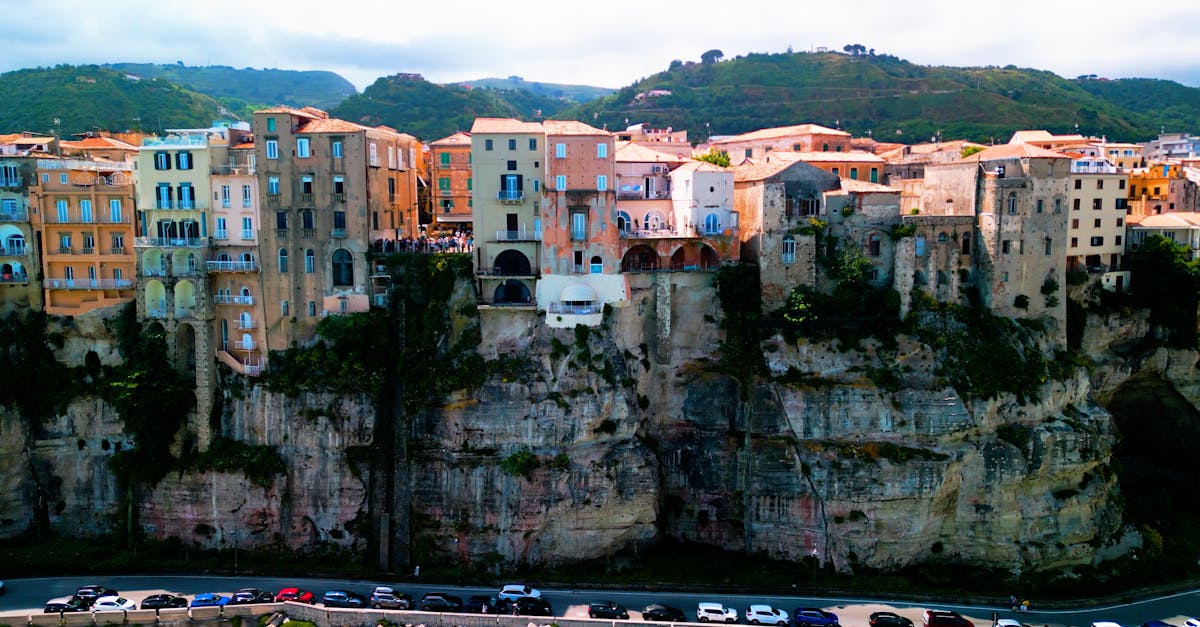 A breathtaking view of Tropea, Italy, with historic buildings perched on majestic cliffs under a vibrant sky.