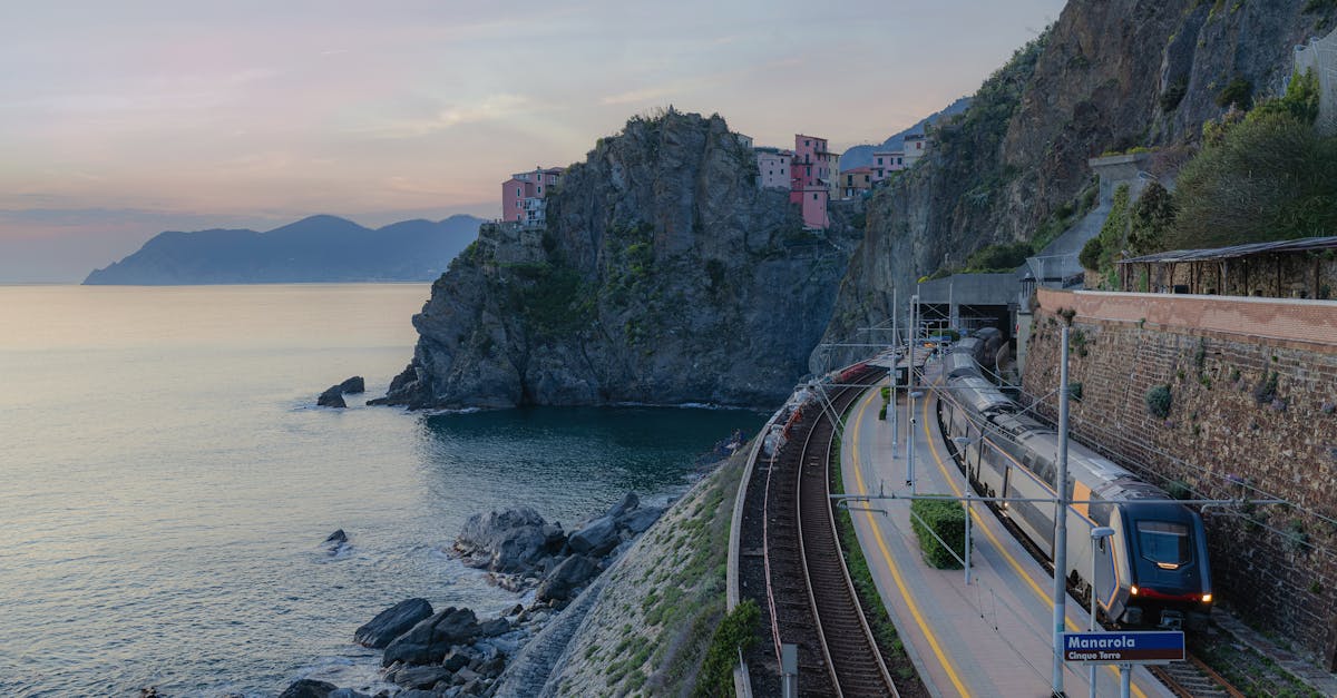 Scenic view of a train passing along cliffs near Manarola, Cinque Terre at sunset.