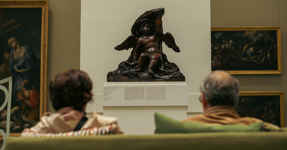 Two adults admire a classic sculpture in a Budapest museum filled with historic paintings.