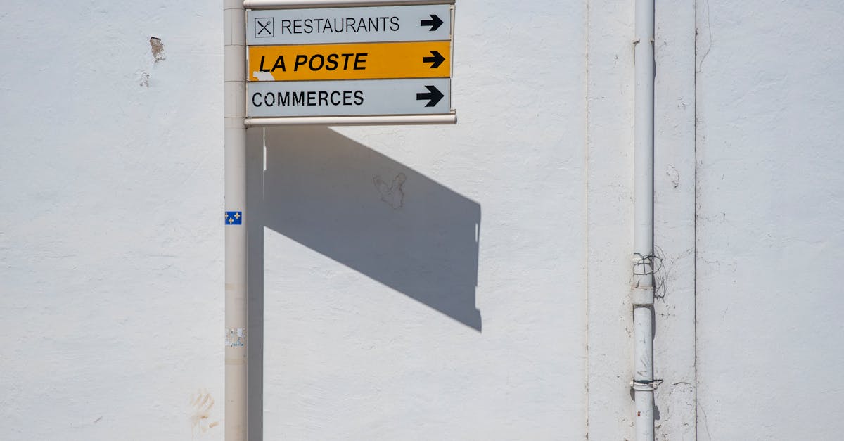 Street direction sign pointing towards La Poste, restaurants, and commerces.