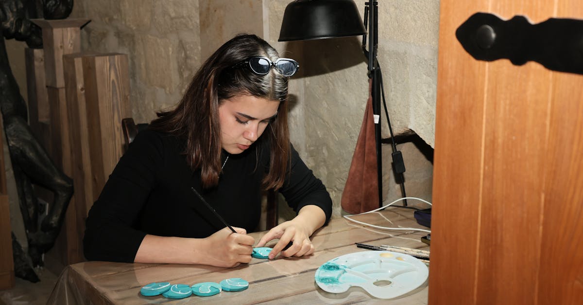 Woman artist focused on painting stones in a rustic indoor studio setting.