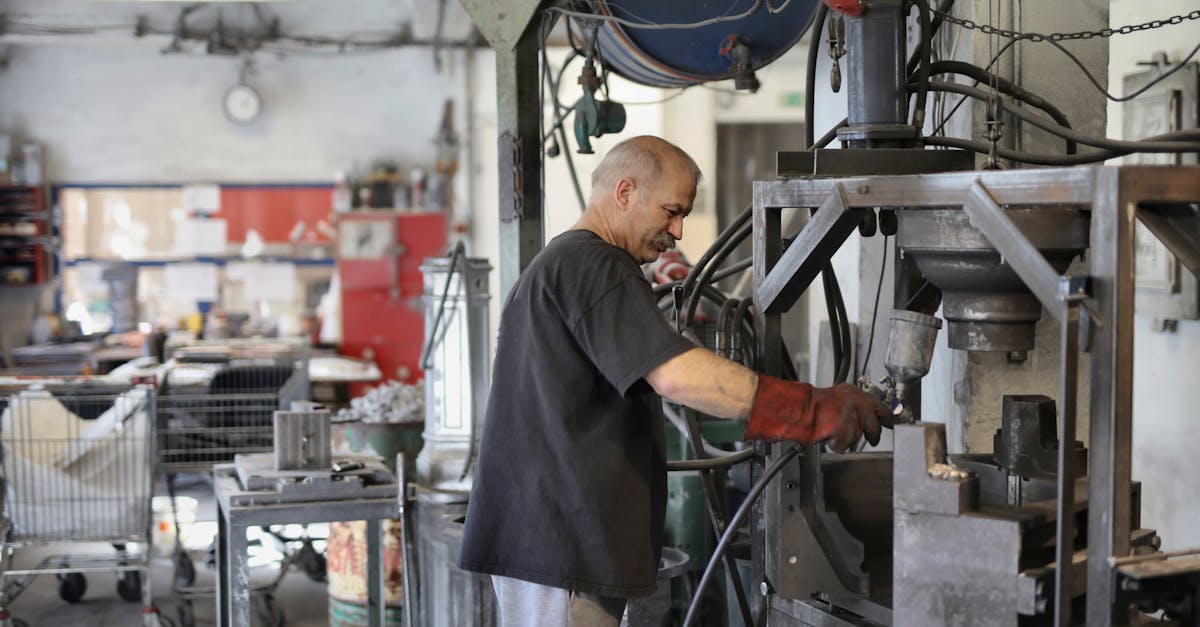 Side view of senior white hair craftsman with mustache working on machine in workshop