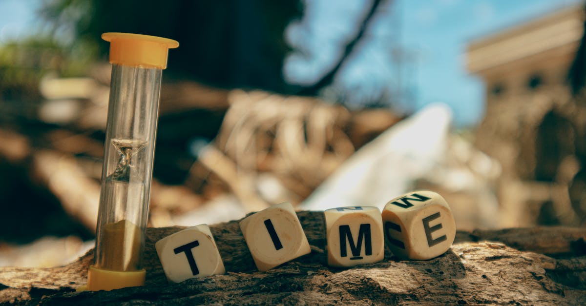 Hourglass and wooden blocks with letters spelling 'TIME' on a sunny day outdoors.