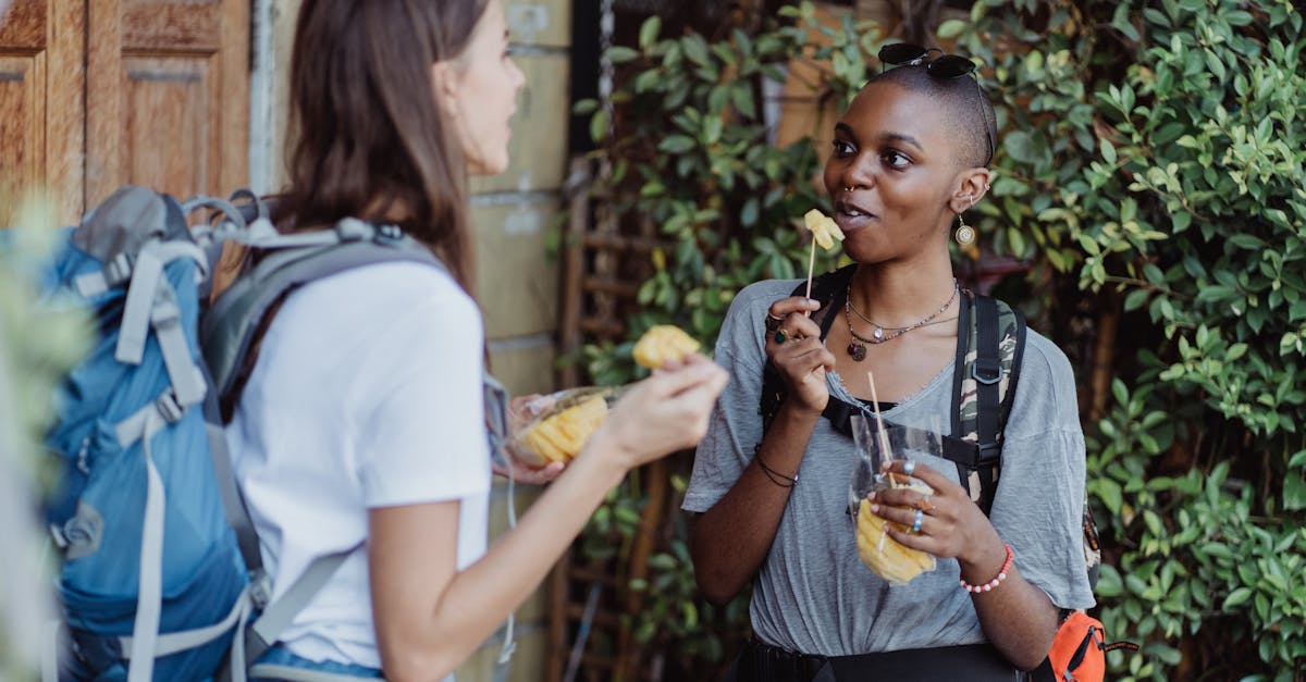 Two women hikers enjoying fresh fruit while backpacking outdoors, capturing a vibrant lifestyle moment.