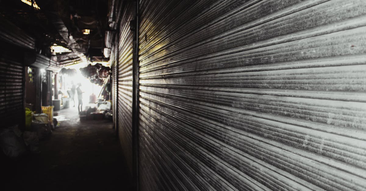 A dark alleyway with shuttered shops and a distant silhouette, evoking mystery and urban decay.