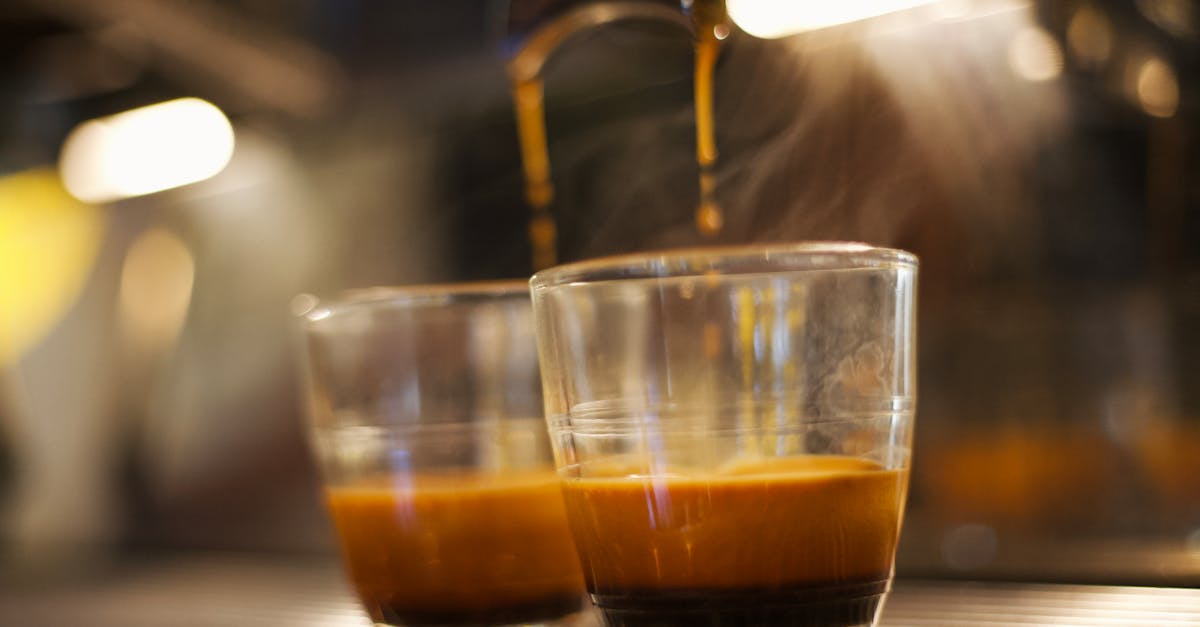 Close-up of espresso shot brewing in clear glass, showcasing coffee richness and steam.