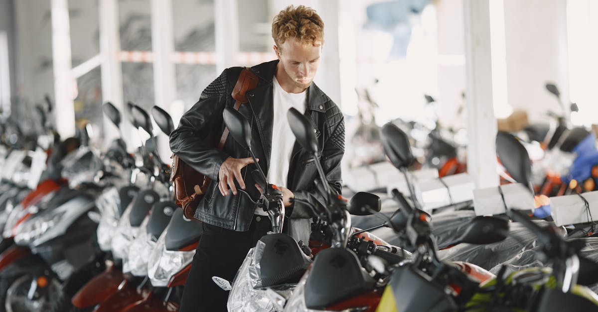 A young man examines a row of motorcycles inside a motor dealership, showcasing interest and choice.
