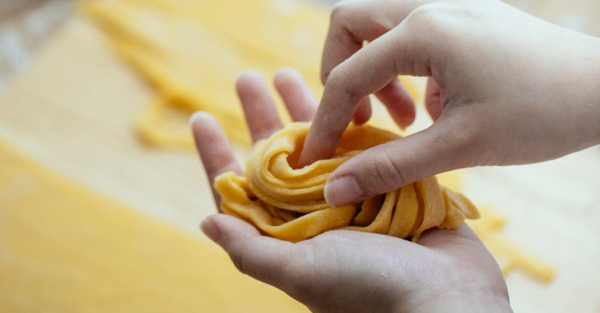 Female hands rolling long stripes of raw homemade noodles preparing for cooking Asian food