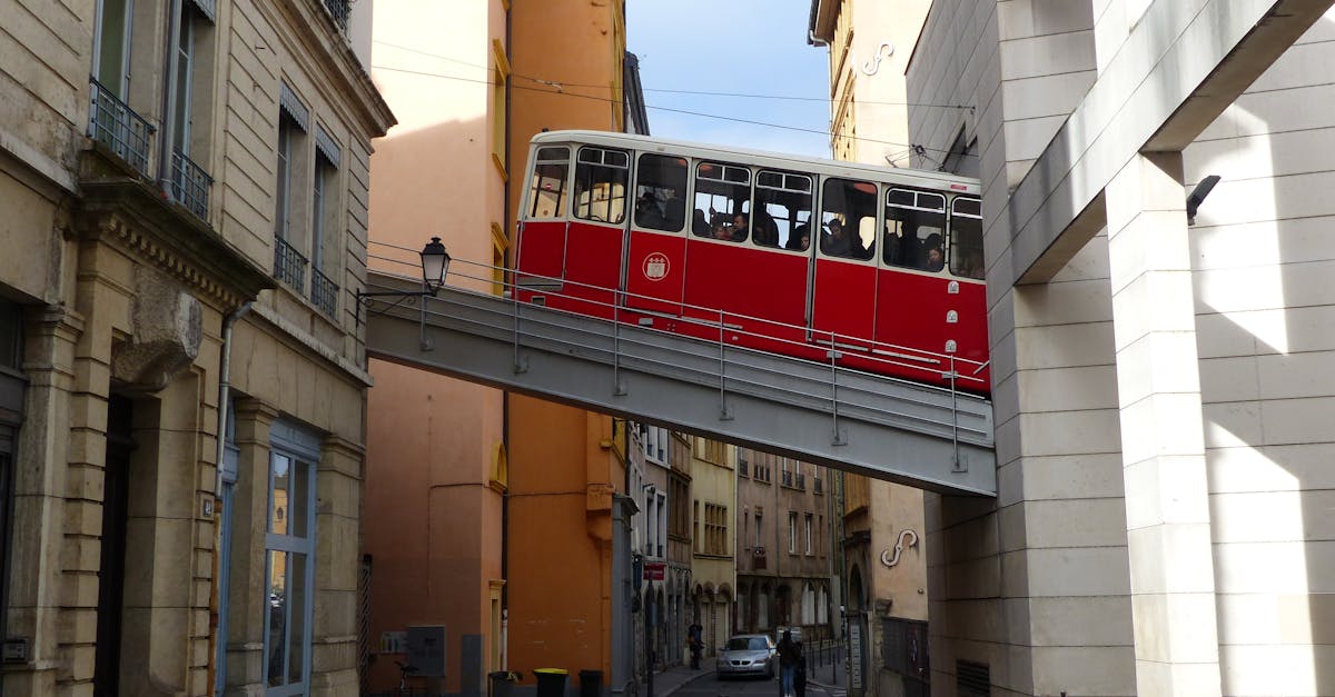 Aged red cable car driving in old district of Lyon between shabby buildings on sunny day